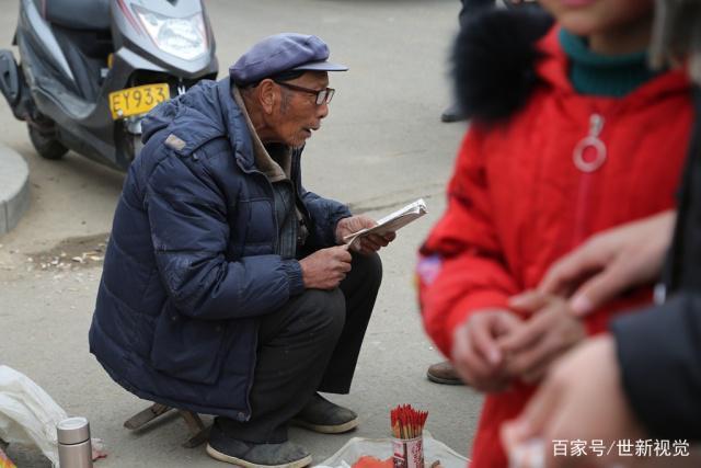 一位长者戴着老花眼镜,手里拿着一本卦书,正在帮一位老奶奶算命